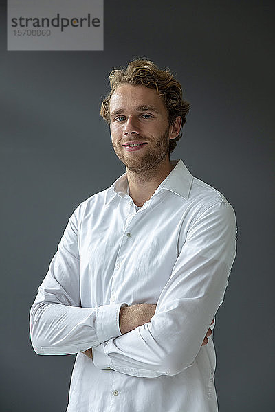 Porträt eines jungen lächelnden Geschäftsmannes mit weißem Hemd  der in die Kamera schaut