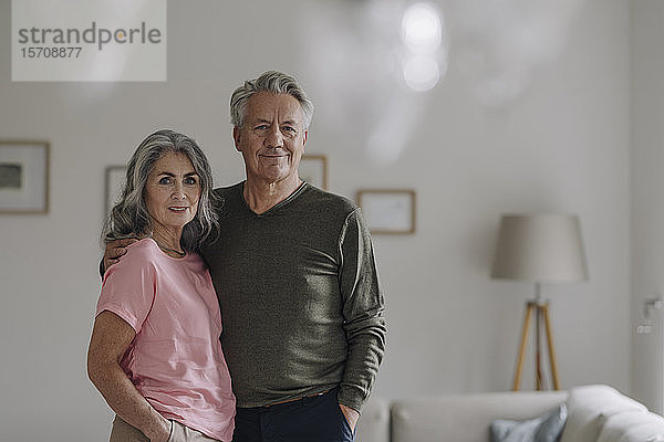 Porträt eines selbstbewussten älteren Paares  das zu Hause im Wohnzimmer steht