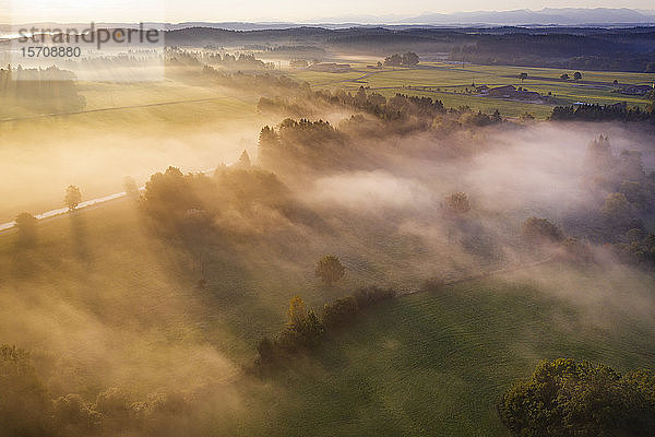 Deutschland  Bayern  Geretsried  Luftaufnahme einer von Nebel umhüllten Landschaft bei Sonnenaufgang