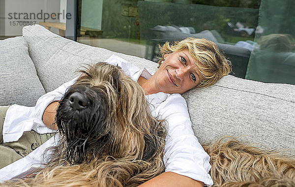 Porträt einer Frau  die sich mit Hund auf der heimischen Terrasse entspannt
