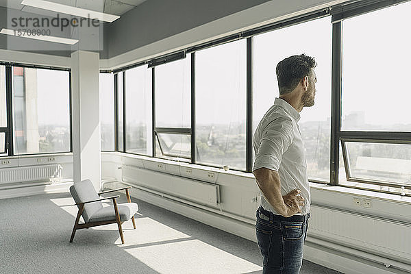 Ein reifer Geschäftsmann schaut in einem leeren Büro aus dem Fenster