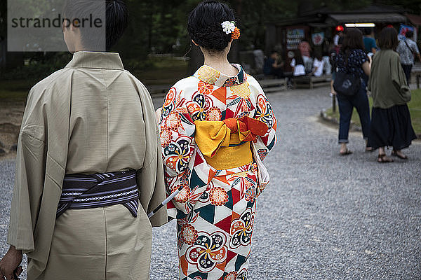 Japan  Präfektur Ishikawa  Kanazawa  Ehepaar mit traditionellen Yukatas  die zusammen im Garten von Kenroku-en spazieren gehen