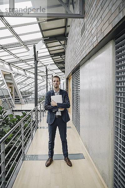 Geschäftsmann hält Tablett in modernem Bürogebäude