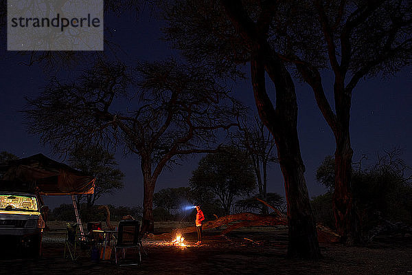 Frau auf einem Campingplatz bei Nacht am Lagerfeuer  Khwai  Botswana