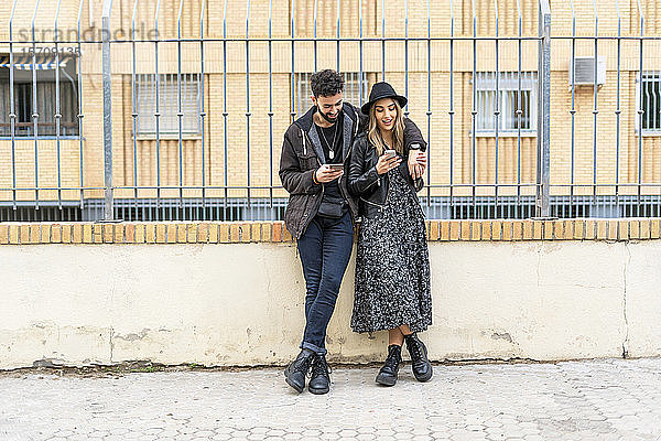 Junges Ehepaar in der Stadt bei der Benutzung ihres Mobiltelefons