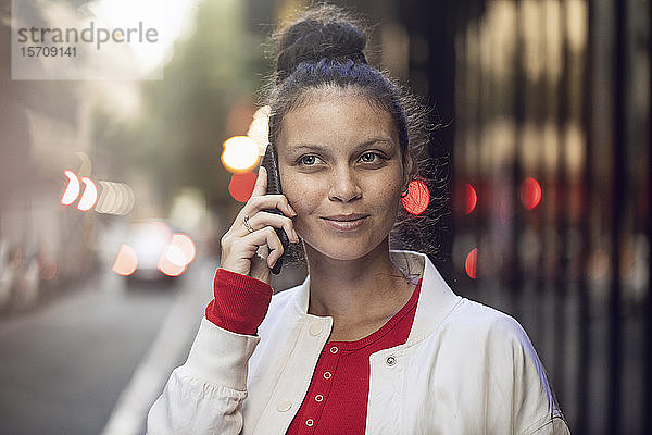 Porträt einer jungen Frau am Telefon in der Stadt
