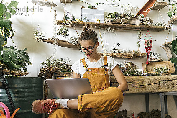 Junge Frau mit Laptop in einem kleinen Gartenbaubetrieb