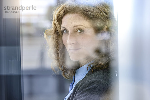 Porträt einer selbstbewussten Geschäftsfrau hinter einer Fensterscheibe