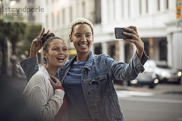 Zwei unbekümmerte junge Frauen  die in der Stadt ein Selfie machen