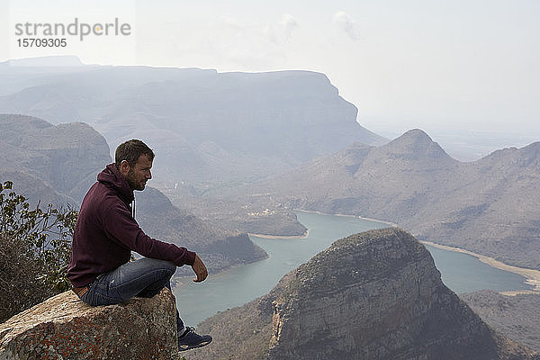 Auf einem Felsen sitzender Mann mit schöner Landschaft als Hintergrund  Blyde River Canyon  Südafrika