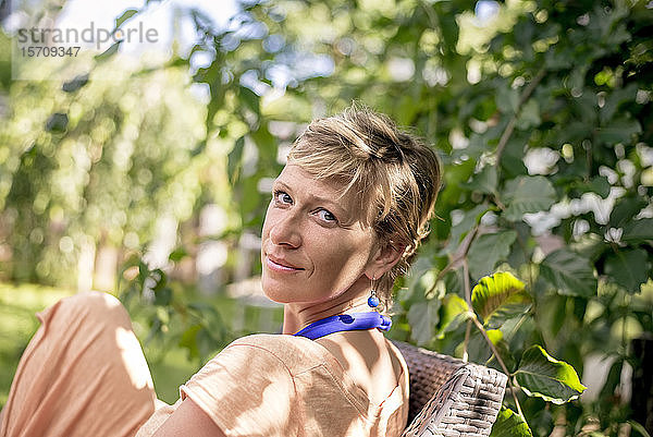 Porträt einer Frau  die sich im Garten entspannt