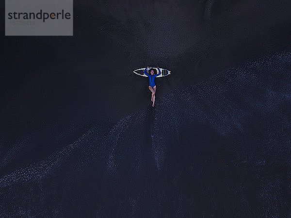 Luftaufnahme einer jungen Frau mit Surfbrett am Strand  Strand von Kedungu  Bali  Indonesien