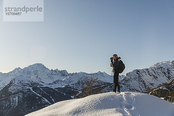 Frau beim Fotografieren einer winterlichen Berglandschaft  Valmalenco  Italien