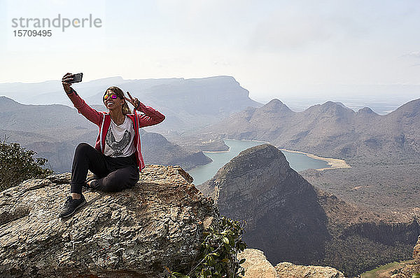 Frau  die mit ihrem Handy einen Selfie mit wunderschönem Landschaftshintergrund aufnimmt  Blyde River Canyon  Südafrika