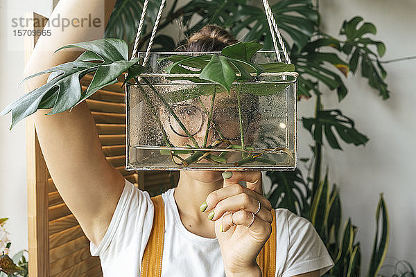 Junge Frau hält Pflanze in einem Kasten mit Wasser