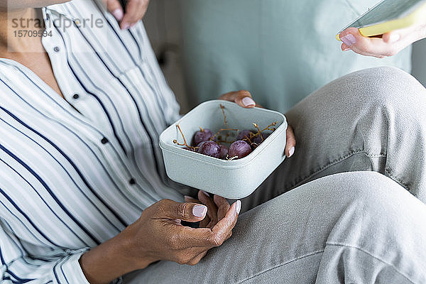 Nahaufnahme einer Frau  die eine Lunchbox mit Trauben hält
