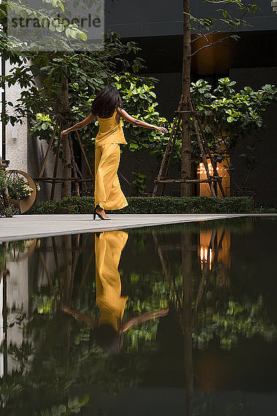 Rückenansicht einer modisch gekleideten Frau in Gelb beim Tanzen in der Stadt