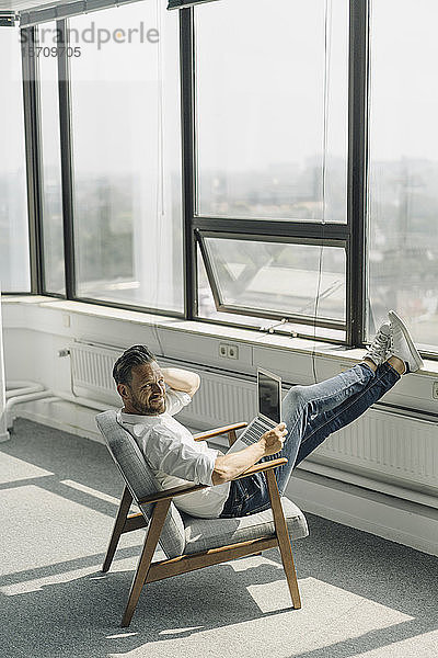 Reifer Geschäftsmann benutzt Laptop in leerem Büro