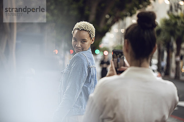Junge Frau posiert für ein Smartphone-Foto in der Stadt
