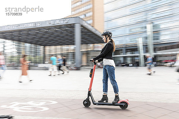 Frau fährt E-Scooter in der Stadt  Berlin  Deutschland  Berlin  Deutschland