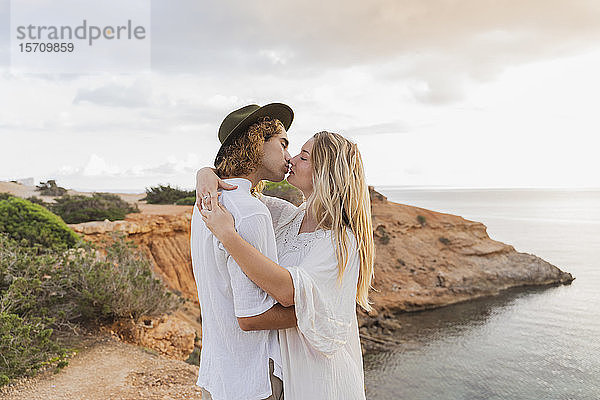 Verliebtes junges Paar küsst sich vor dem Meer  Ibiza  Balearen  Spanien