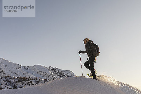 Frau wandert mit Schneeschuhen im Neuschnee in den Bergen bei Sonnenuntergang  Valmalenco  Italien