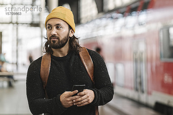 Junger Mann mit Smartphone auf dem Bahnsteig  Berlin  Deutschland