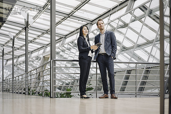 Geschäftsmann und Geschäftsfrau mit Tablett stehend in modernem Bürogebäude