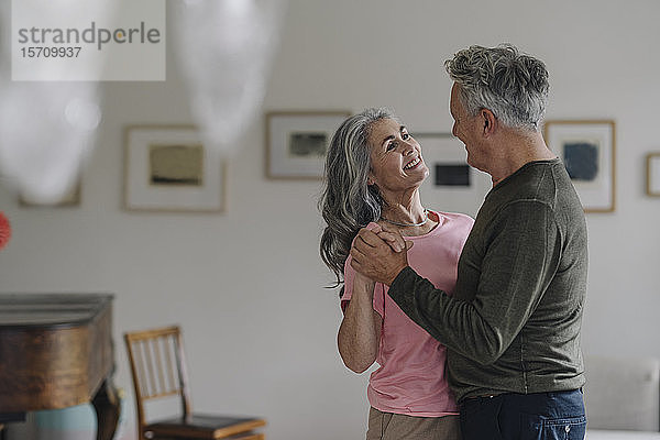 Glückliches älteres Paar tanzt zu Hause im Wohnzimmer