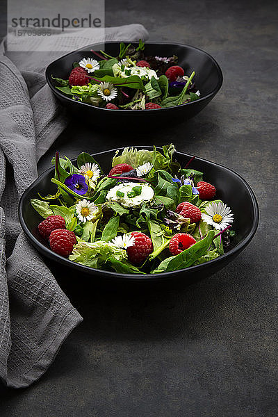Schüssel frischer Salat mit Rucola  Spinat  Mangold  Eichenblatt  Lollo Rosso Salat  Maissalat  Himbeeren  Frischkäse  Schnittlauch und essbaren Blumen