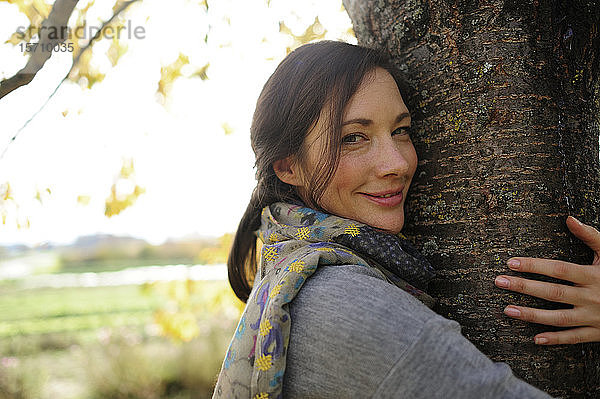 Porträt einer Frau  die einen Baum umarmt