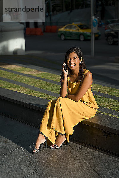Porträt einer lächelnden Frau am Telefon in der Stadt