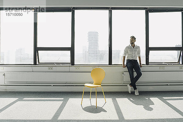 Ein reifer Geschäftsmann steht am Fenster in einem leeren Büro