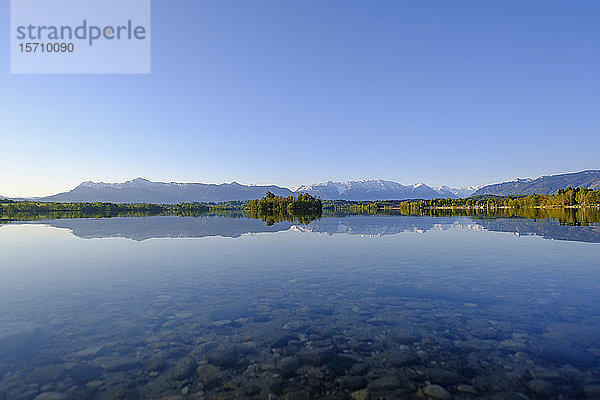 Deutschland  Bayern  Uffing am Staffelsee  Blick auf den Staffelsee  in dem sich der klare Himmel und die umliegenden Berge spiegeln