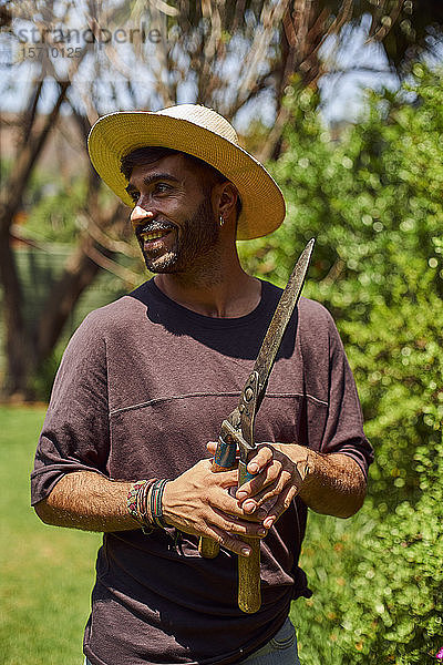 Lächelnder Mann mit Baumschere im Garten