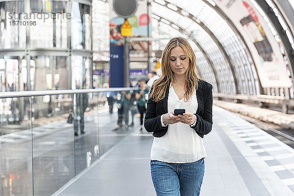 Frau mit Smartphone auf dem Bahnsteig  Berlin  Deutschland