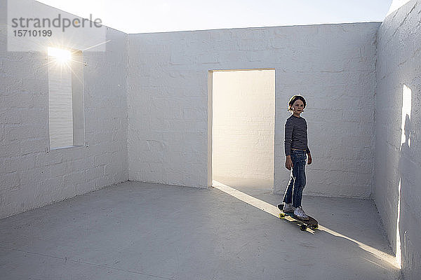 Kleines Mädchen im leeren Raum  auf Skateboard stehend