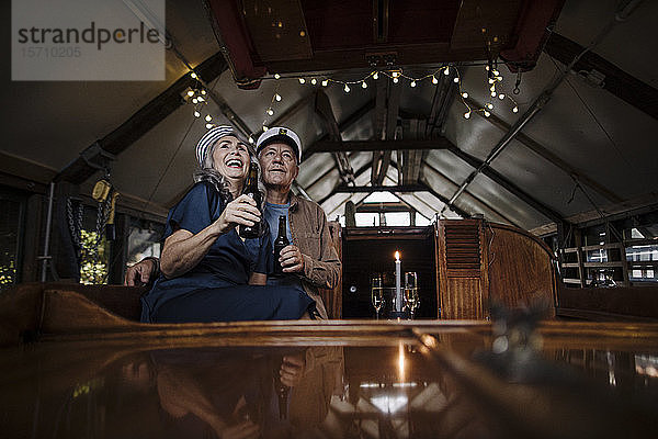 Glückliches älteres Ehepaar bei einem Drink auf einem Boot im Bootshaus