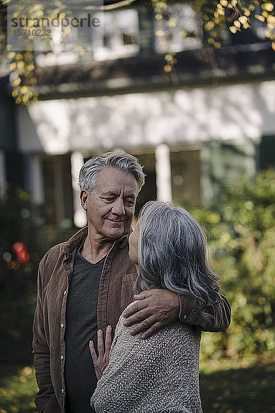 Liebevolles älteres Ehepaar im Herbst im Garten ihres Hauses