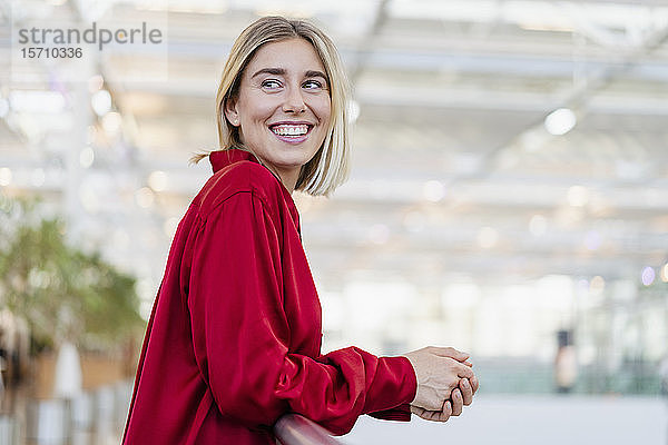 Porträt einer glücklichen jungen Geschäftsfrau an einem Geländer stehend