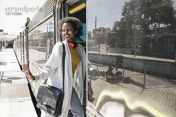 Lächelnde junge Frau beim Einsteigen in einen Zug