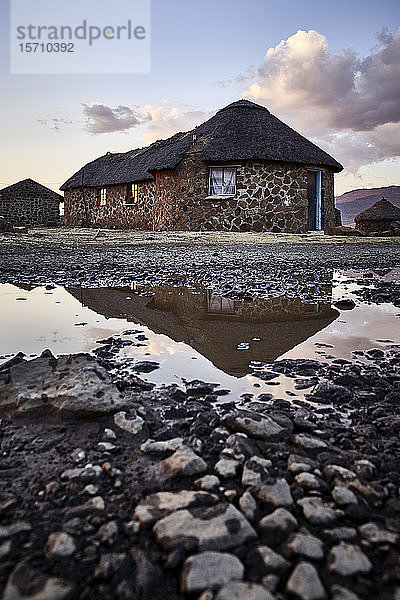 Traditionelle Steinhäuser und Reflexion in einer Pfütze  Lesotho