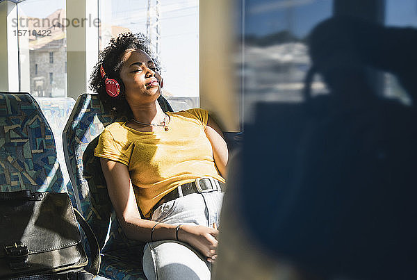 Junge Frau mit Kopfhörern entspannt sich in einem Zug