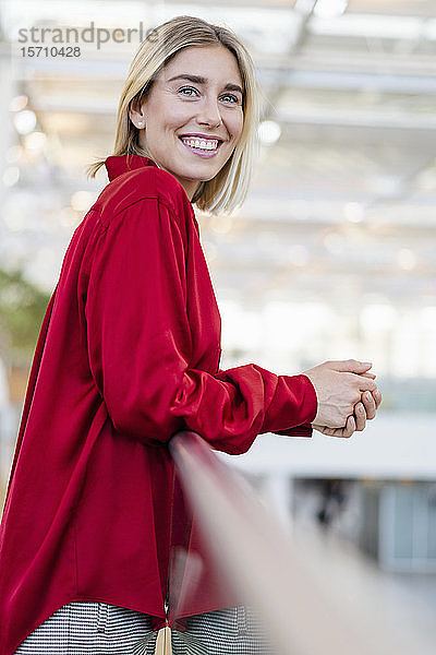 Porträt einer lächelnden jungen Geschäftsfrau  die an einem Geländer steht