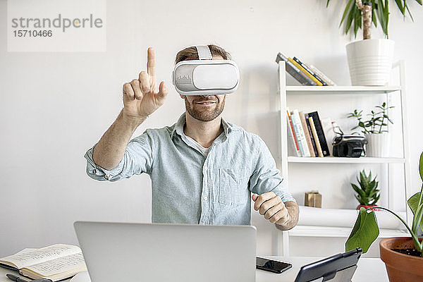 Mann mit VR-Brille am Schreibtisch im Büro