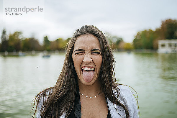 Bildnis einer Frau an einem See mit herausgestreckter Zunge