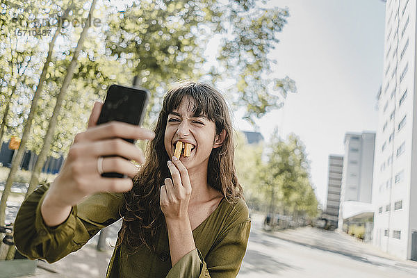 Porträt einer brünetten Frau  die einen Selfie nimmt  Kaninchenzähne mit Pommes Frites
