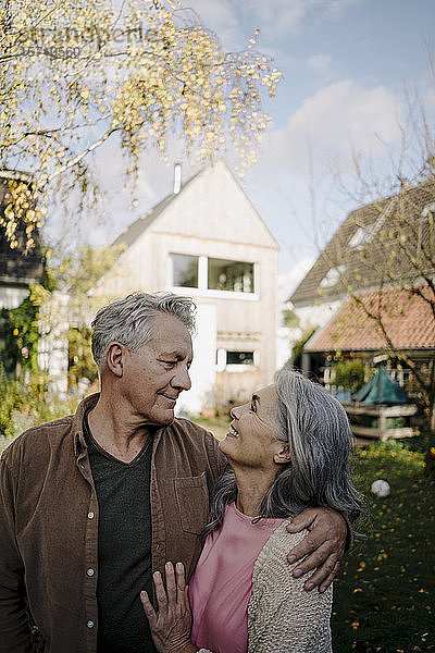 Glückliches älteres Ehepaar im Herbst im Garten ihres Hauses