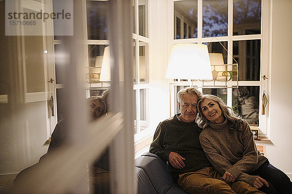 Porträt eines älteren Paares  das sich abends zu Hause auf der Couch entspannt