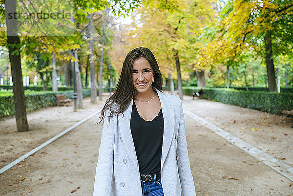 Porträt einer lächelnden Frau  die in einem Park steht